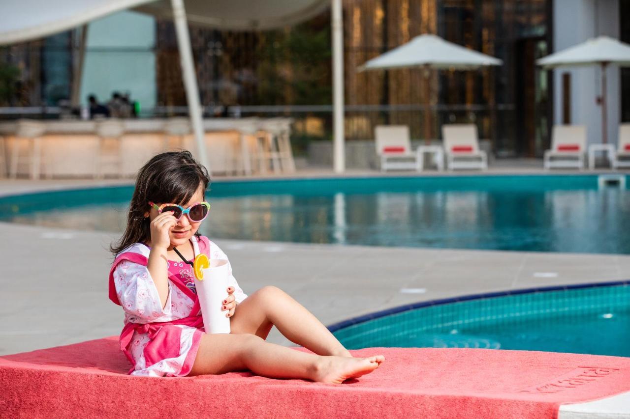 Al Jaddaf Rotana Suite Hotel Dubai Esterno foto A child wearing sunglasses